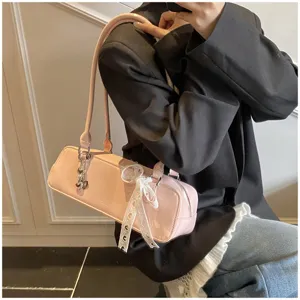 Pink patent leather baguette shoulder bag with cute white lace bow and chic charm pendant.