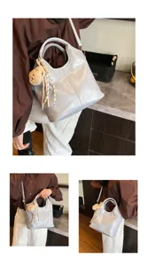 Graue Handtasche aus weichem Leder Detail, Freizeittasche mit Bärenanhänger und Schultergurt.
