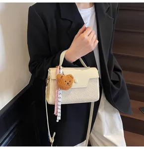 Detailed view of stylish white crossbody bag with cute plush bear charm and chic ribbon decor.