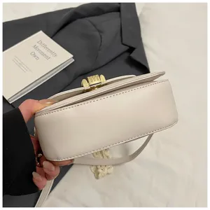Vista detallada de un bolso bandolera blanco elegante con cierre metálico para diario.
