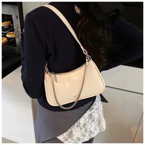 Vista detallada del bolso de hombro beige de cuero suave con elegante correa de cadena metálica.