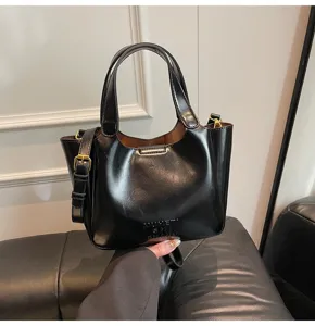 Detailansicht der schwarzen Leder-Eimerhandtasche mit Metallschnalle und Schultergurt.