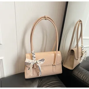 Detail view of the elegant beige patent leather shoulder bag with chic bow and dual straps.