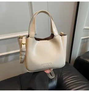 Detailansicht der eleganten, beige Eimerhandtasche mit feinen Nähten und Metallbeschlägen.