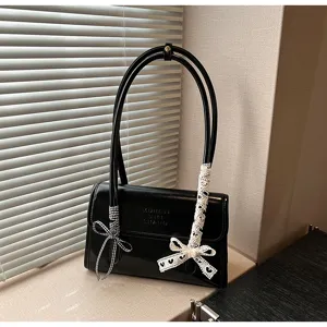 Detailed view of the black shoulder bag strap featuring elegant lace bow decoration.