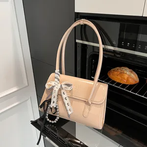 Elegant beige patent leather shoulder bag for women, featuring a chic bow ribbon and pearls.