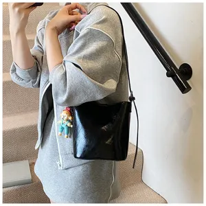 Detailed view of a chic black glossy bucket bag with a cute charm for women casual use.