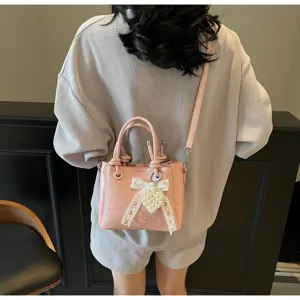 Stylish pink bucket bag for women, featuring casual shoulder strap and cute pearl bow charm.