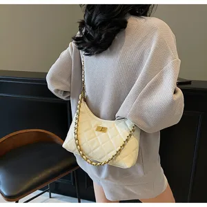 White quilted underarm bag detail, featuring metallic chain strap and turn-lock closure design.