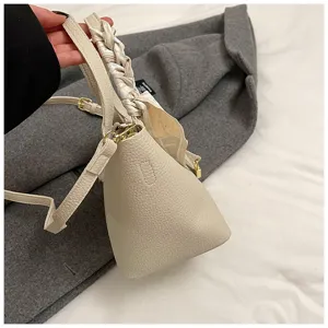 Minimalistische Eimer Tasche aus Kunstleder mit geflochtenem Schal Griff und Umhängegurt.