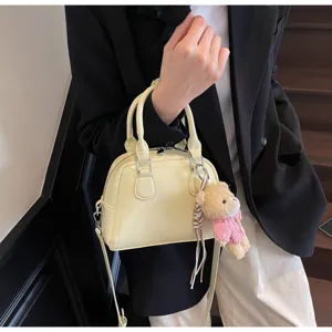 Dettaglio della borsa Boston in vernice gialla, elegante borsa da lavoro con ciondolo orso.