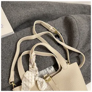 Beige Leder Eimer Tasche für Damen, stilvolle Umhängetasche mit elegantem Schal Detail.