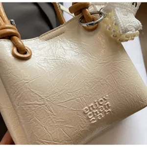 Detailed view of the stylish cream handbag featuring unique textured leather and chic knotted handles.