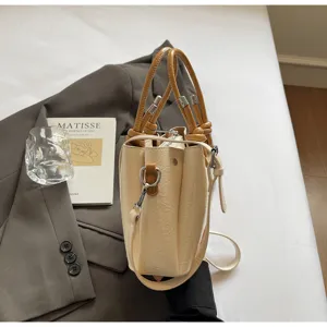 Detailed view of the stylish creamy-white bucket bag with brown handles and elegant texture.