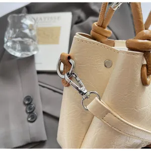 Close-up detail of stylish women bucket bag, PU leather, knotted handles, metal hardware.