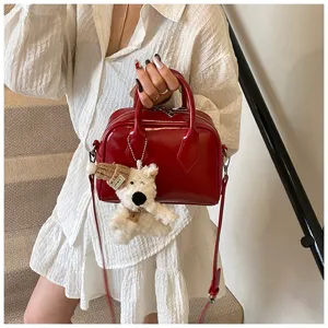 Red soft leather bowling bag detail, elegant handheld pillow bag with cute bear pendant.