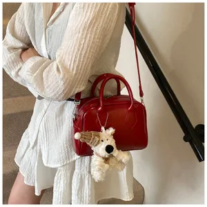Soft leather bowling bag for women, stylish red shoulder handbag with cute plush dog charm.
