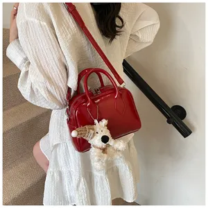 Red soft leather bowling shoulder bag with cute plush dog pendant for women casual commute.