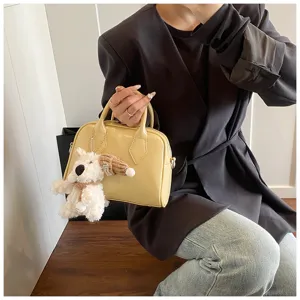 Soft leather bowling handbag for women, chic pillow shoulder bag with cute puppy plush charm.