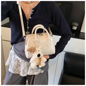 Detailed shot of soft leather bowling bag with cute plush dog pendant, casual style.