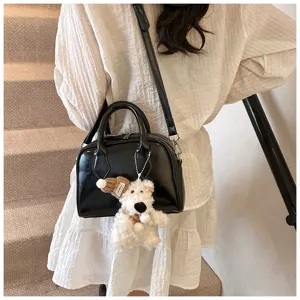 Black glossy bowling bag detail showing soft leather texture and cute plush bear pendant charm.