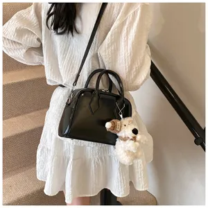 Close-up detail of black soft leather bowling bag with cute puppy keychain and strap.