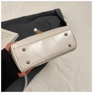 White soft leather bowling bag bottom detail, fashion casual women handbag with metal feet.