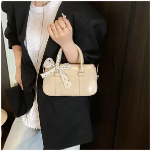 Detailed view of the elegant beige patent mini handbag featuring a charming bowknot accent.