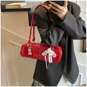 Red patent leather baguette shoulder bag with cute bow detail and heart charm for daily wear.