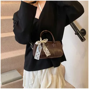 Brown patent leather mini handbag with polka dot ribbon bow, vintage shoulder bag detail.