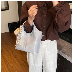 Detailansicht der weichen Leder Handtasche mit hellem grauem Finish und dem süßen Bären-Anhänger.