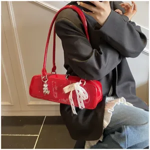 Red patent leather baguette shoulder bag with white lace bow and cute metal pendant for women.