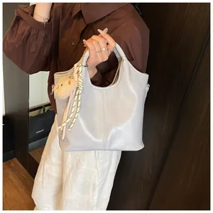 Detailansicht der grauen Damen Tragetasche aus weichem Leder mit Bärenanhänger und Schultergurt.