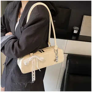 Chic beige baguette shoulder bag with stylish bow ribbon and heart charm for women daily wear.