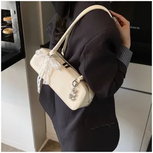 Chic white patent leather baguette shoulder bag with cute lace bow and heart charm for women.