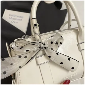Detailed view of the white retro small square handbag with elegant polka dot ribbon handle wrap.
