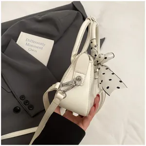 Detail view of a white PU leather handbag featuring a chic polka dot scarf and shoulder strap.