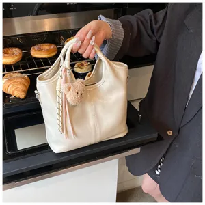 Detailaufnahme der minimalistischen Damen Weichleder Tasche mit Bärenanhänger und Troddel.
