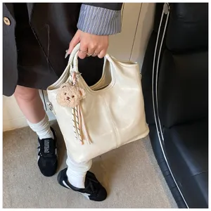 Nahaufnahme der eleganten weichen Ledertasche mit einem niedlichen Bärenanhänger Detail.