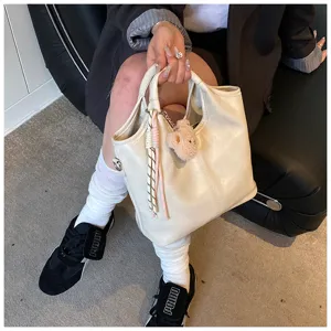 Detailansicht der weichen Ledertasche mit süßem Bärenanhänger und geflochtenem Seil.