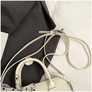 Handbag close up detail showcasing adjustable shoulder strap and decorative polka dot scarf.
