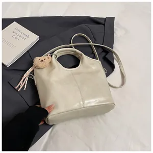 Detailansicht einer minimalistischen hellbeige Kunstleder Handtasche mit Bärenanhänger.