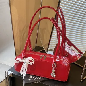 Red patent leather baguette shoulder bag with white lace bow and silver heart charms for women.