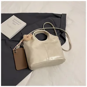 Detailaufnahme der weichen Ledertasche mit süßem Bärenanhänger in eleganter Szene.