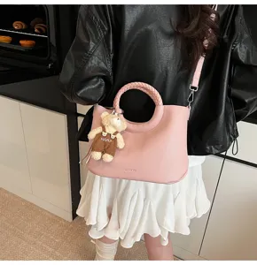 Stilvolle rosa Handtasche mit rundem Griff und Bärenanhänger für Damen, ideal für den Alltag.