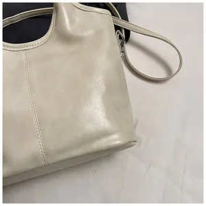Detailaufnahme einer weichen, hellen Damentasche aus Leder mit feinen, sauberen Nähten.