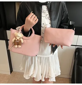 Detailansicht der rosa Handtasche aus PU-Leder mit geflochtenem Griff und Bären-Anhänger.