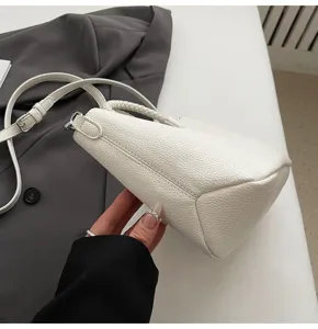 Nahaufnahme Detail der weißen strukturierten Schultertasche mit geflochtenem Griff.
