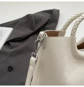 Weißer Kunstleder Shopper Umhängetasche Detail mit geflochtenen Griffen und Metallverschluss.