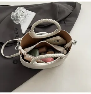 Detailansicht des Innenraums und der geflochtenen Griffe dieser weißen Beuteltasche.